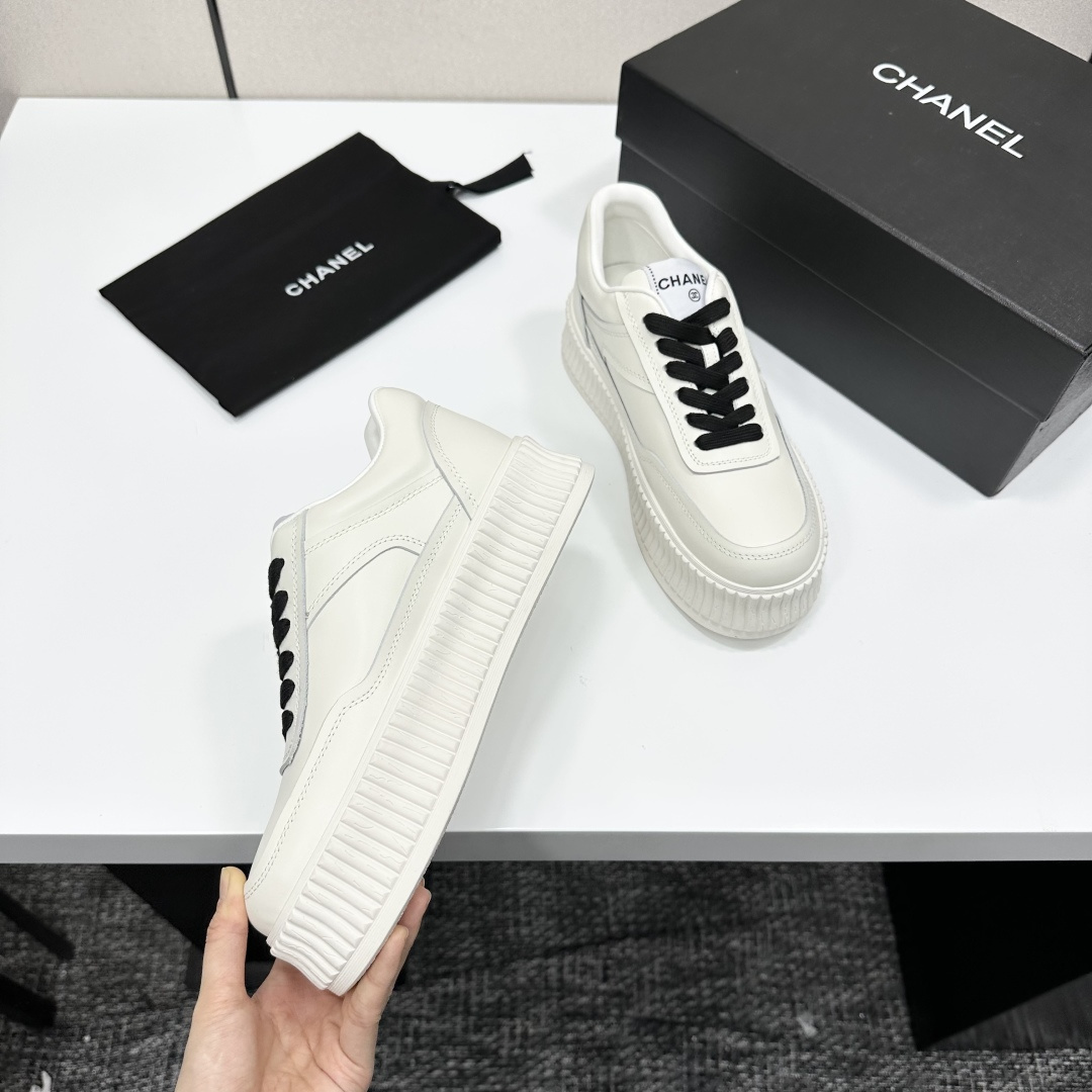 A pair of Chanel white leather platform sneakers with black laces and the iconic CC logo on the side. - Hình 9