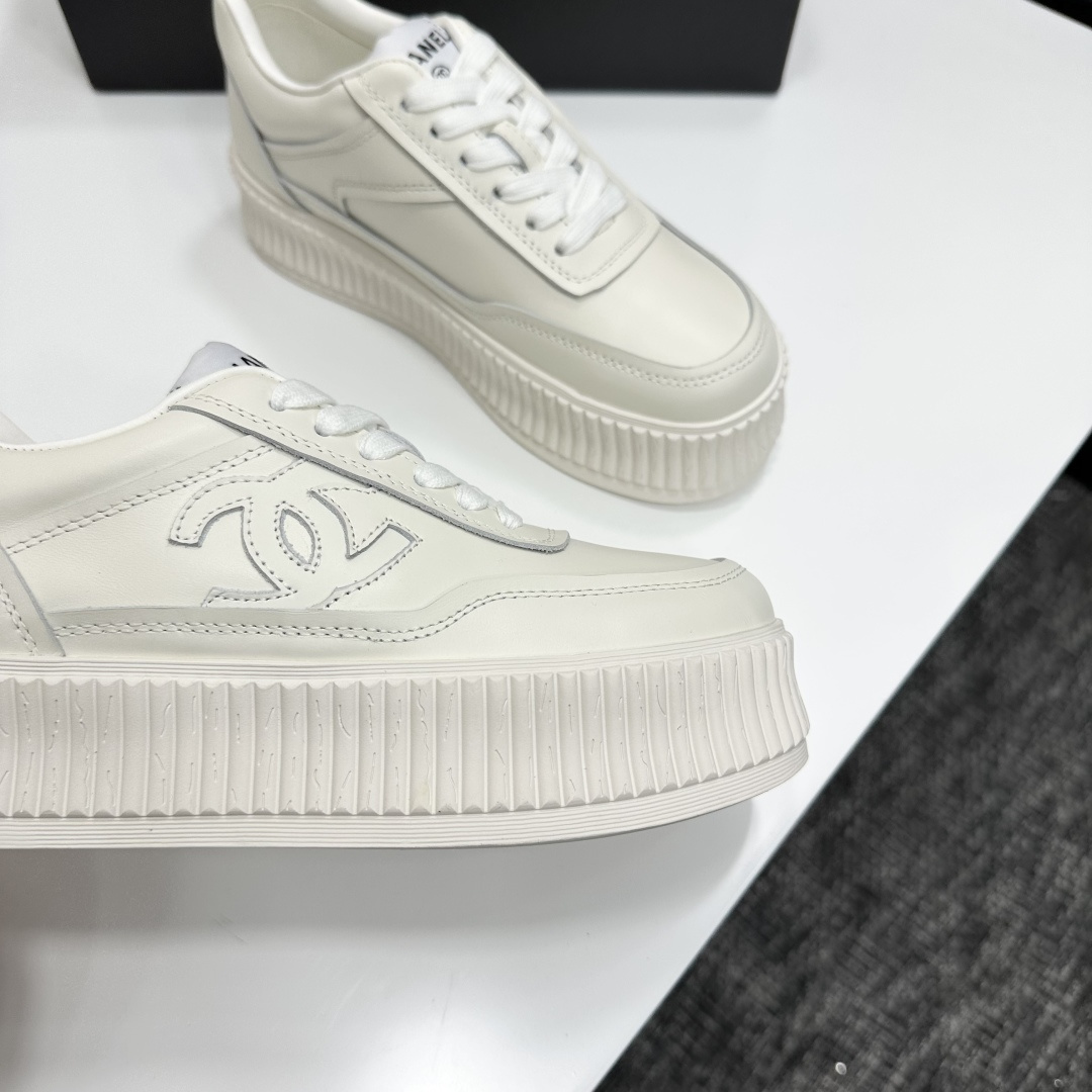 A pair of Chanel white leather platform sneakers with interlocking CC logo displayed on a black designer box. - Hình 10