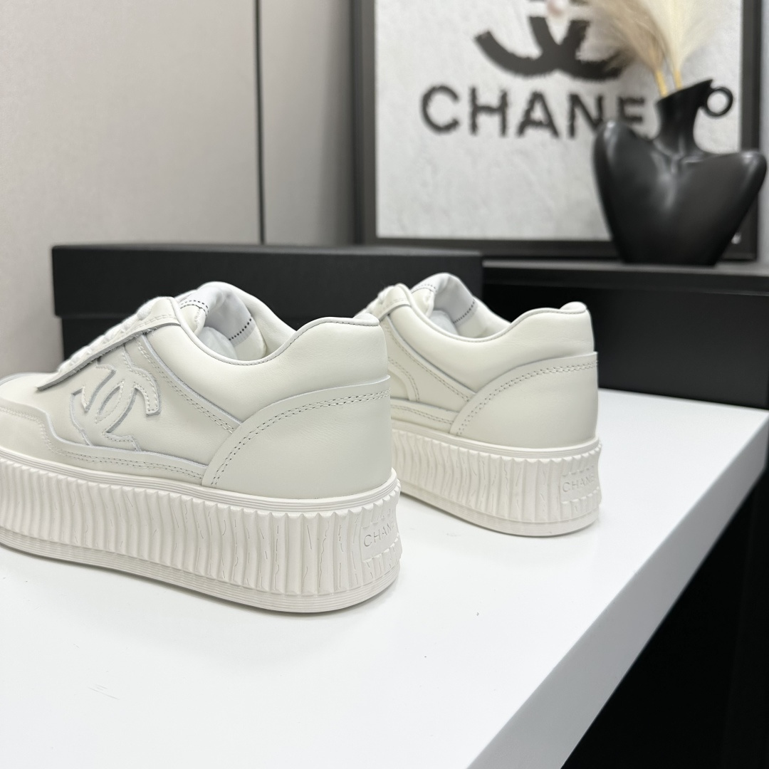 A pair of Chanel white leather platform sneakers with interlocking CC logo displayed on a black designer box. - Hình 8
