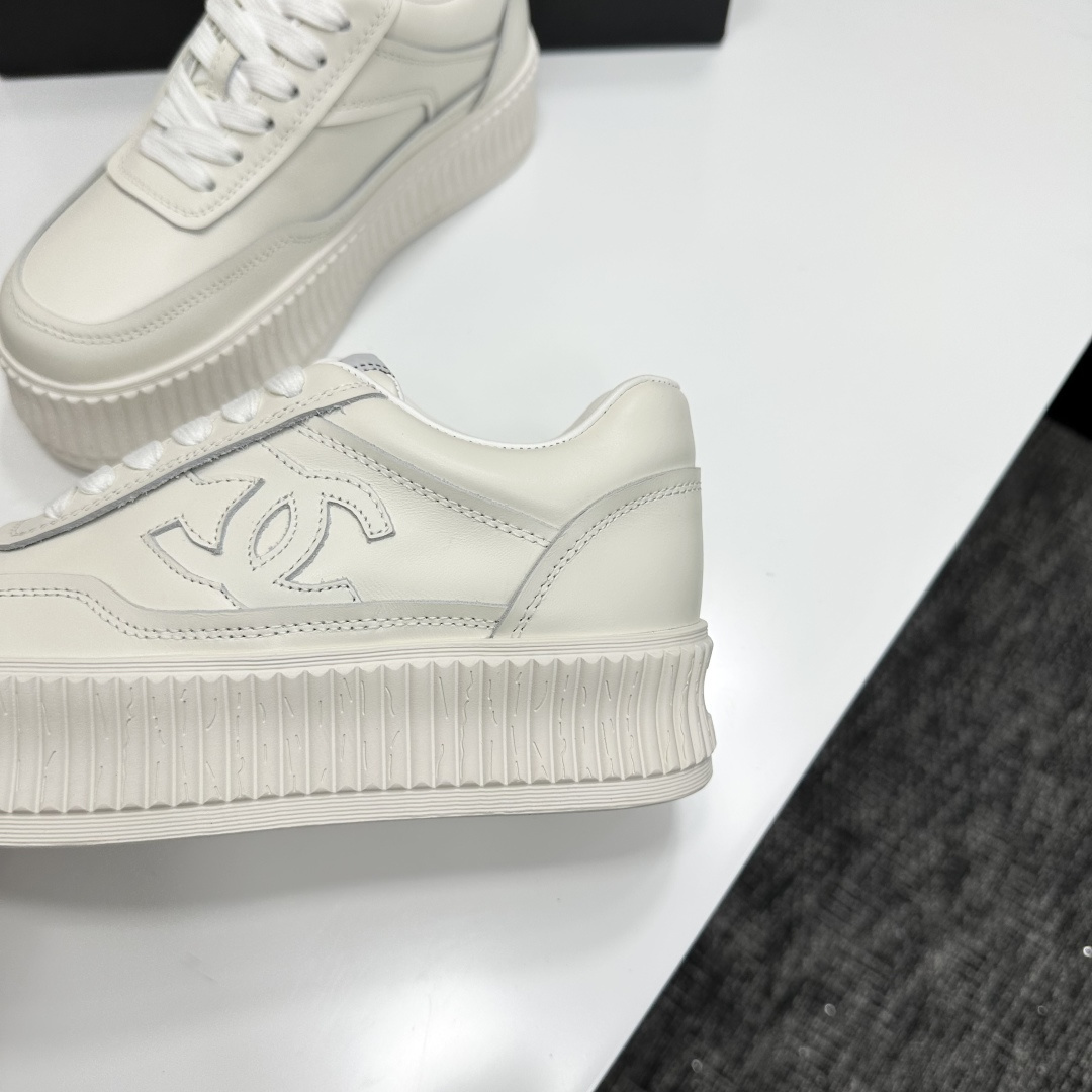 A pair of Chanel white leather platform sneakers with interlocking CC logo displayed on a black designer box. - Hình 7