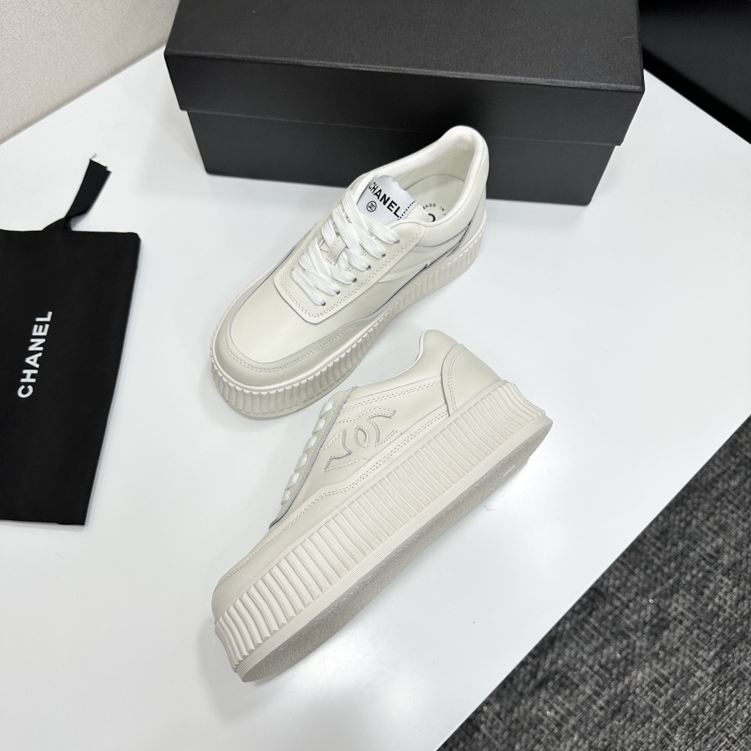 A pair of Chanel white leather platform sneakers with interlocking CC logo displayed on a black designer box. - Hình 6