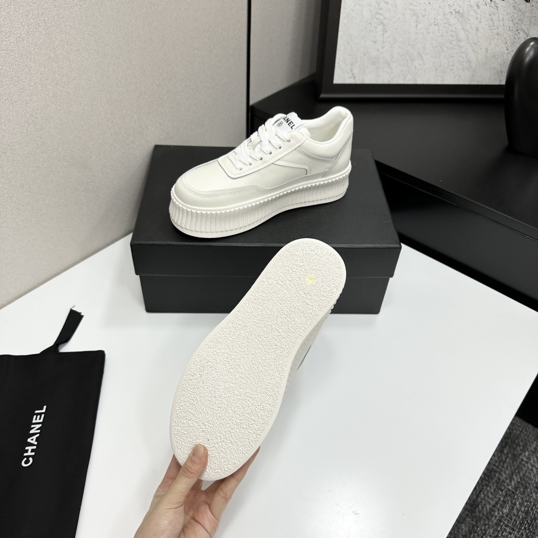 A pair of Chanel white leather platform sneakers with interlocking CC logo displayed on a black designer box. - Hình 5