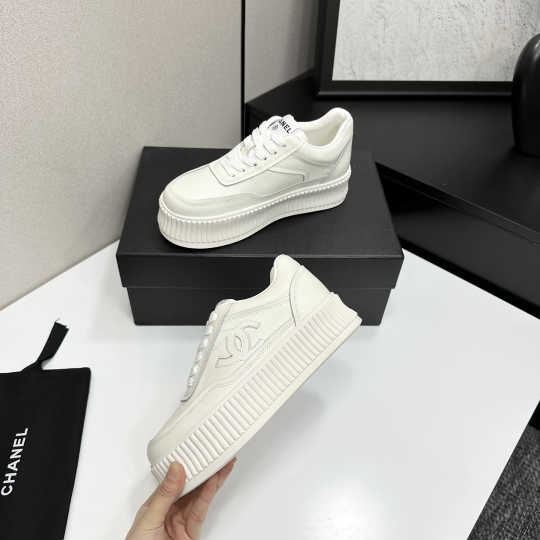A pair of Chanel white leather platform sneakers with interlocking CC logo displayed on a black designer box. - Hình 4