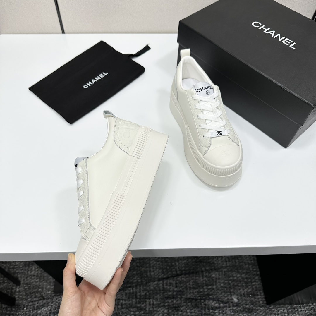 A pair of luxury Chanel white leather platform sneakers with chunky ribbed soles on a black display box. - Hình 8