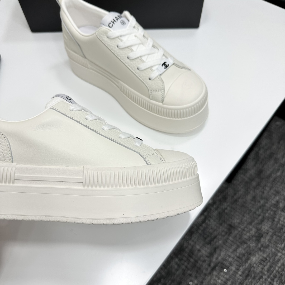 A pair of luxury Chanel white leather platform sneakers with chunky ribbed soles on a black display box. - Hình 7