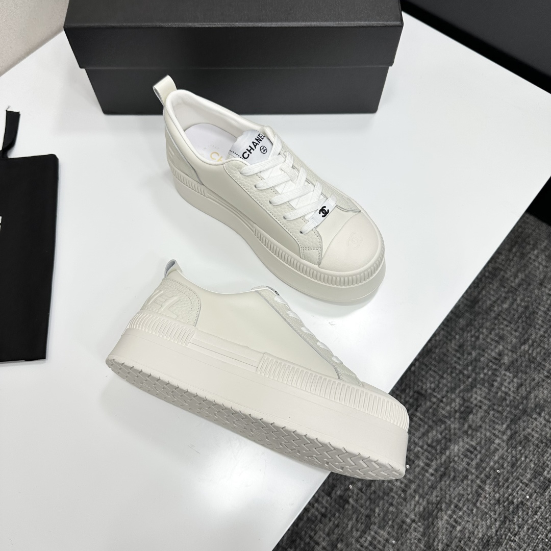 A pair of luxury Chanel white leather platform sneakers with chunky ribbed soles on a black display box. - Hình 6