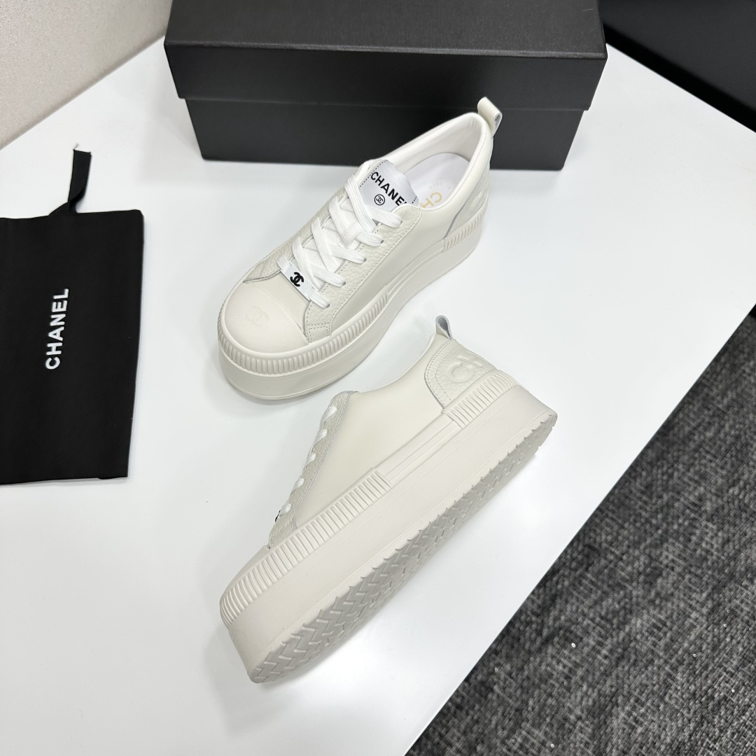 A pair of luxury Chanel white leather platform sneakers with chunky ribbed soles on a black display box. - Hình 4