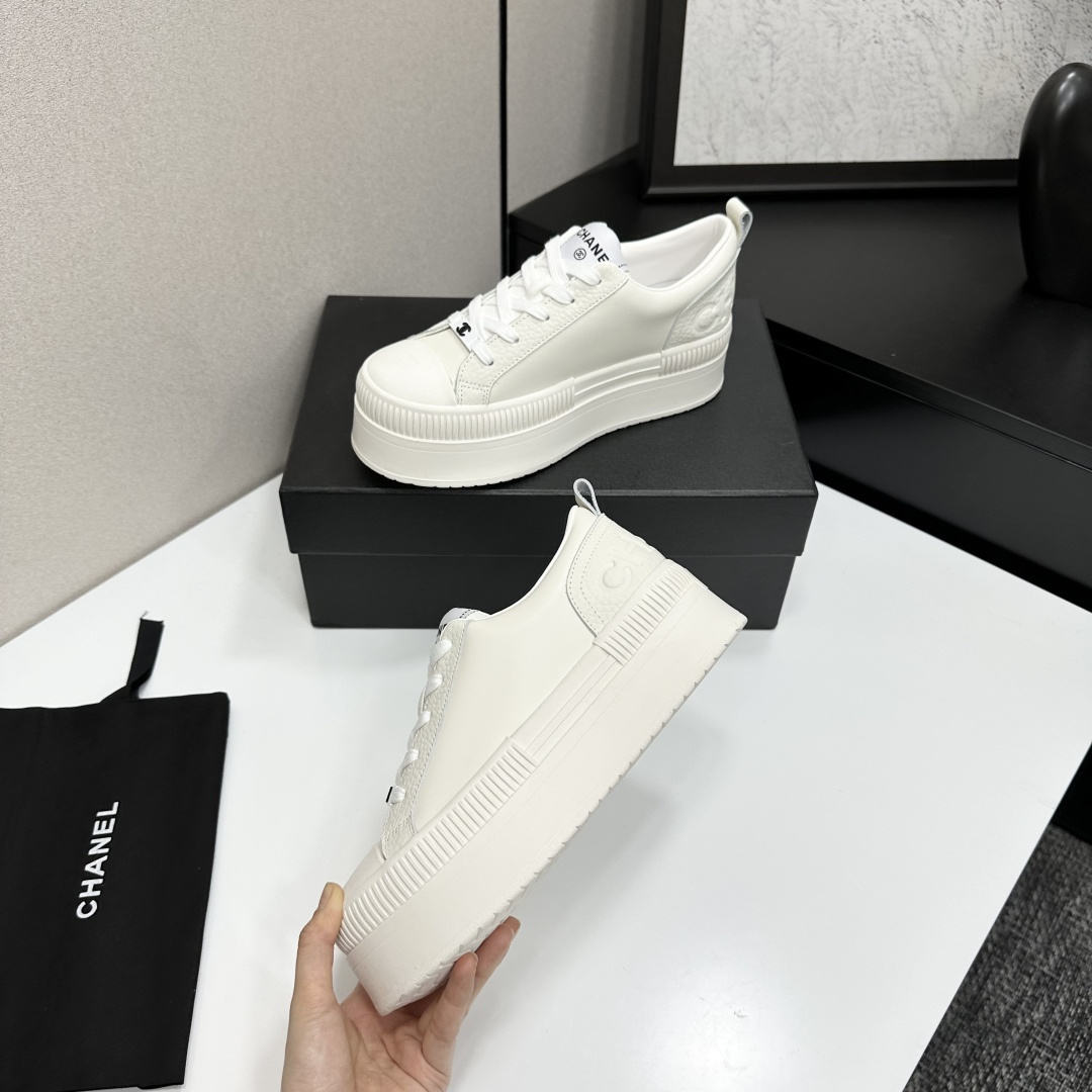 A pair of luxury Chanel white leather platform sneakers with chunky ribbed soles on a black display box. - Hình 3