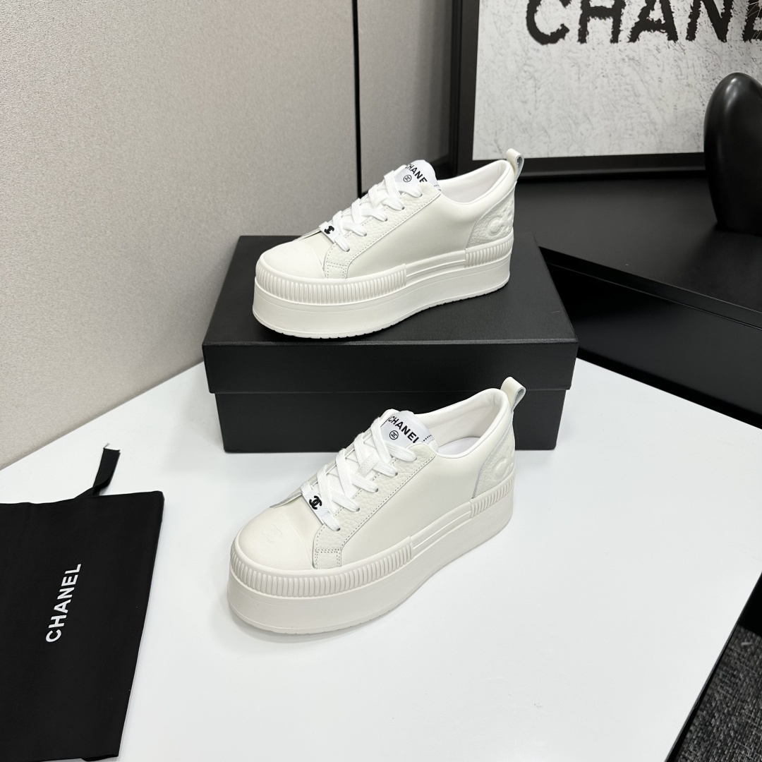 A pair of luxury Chanel white leather platform sneakers with chunky ribbed soles on a black display box. - Hình 2