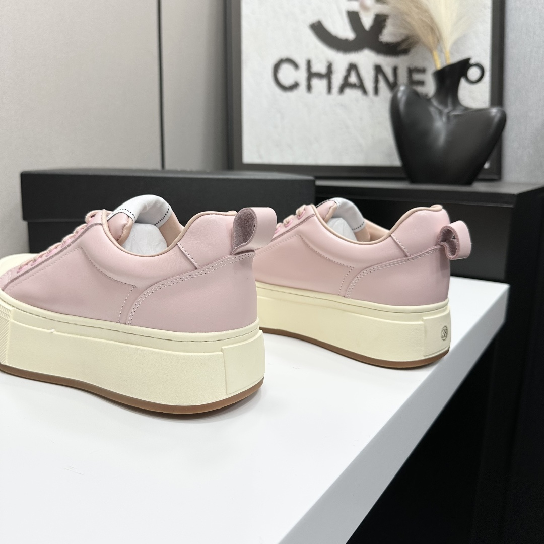 A pair of luxury Chanel pink leather sneakers with thick cream platform soles displayed on a black designer box. - Hình 6