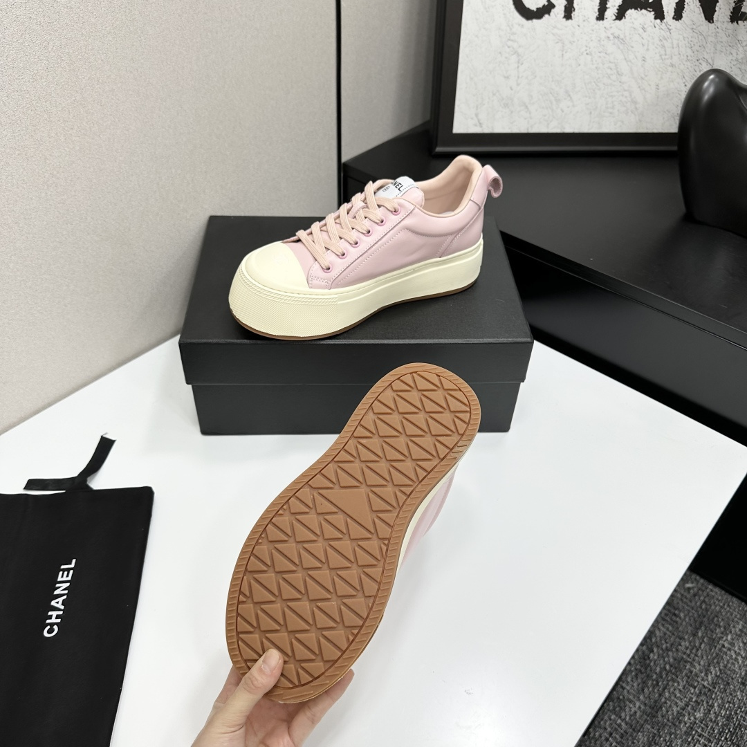 A pair of luxury Chanel pink leather sneakers with thick cream platform soles displayed on a black designer box. - Hình 4