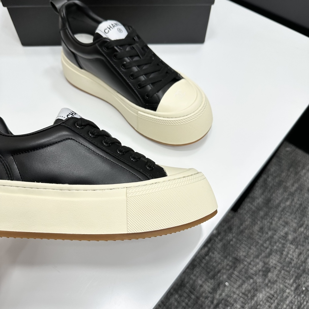 A pair of Chanel black leather sneakers with a thick cream platform sole placed on a black designer box. - Hình 8