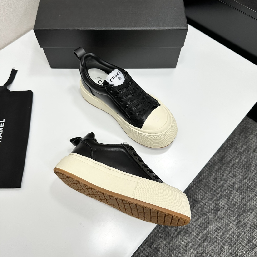A pair of Chanel black leather sneakers with a thick cream platform sole placed on a black designer box. - Hình 7