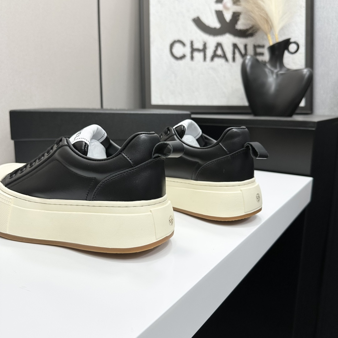 A pair of Chanel black leather sneakers with a thick cream platform sole placed on a black designer box. - Hình 6