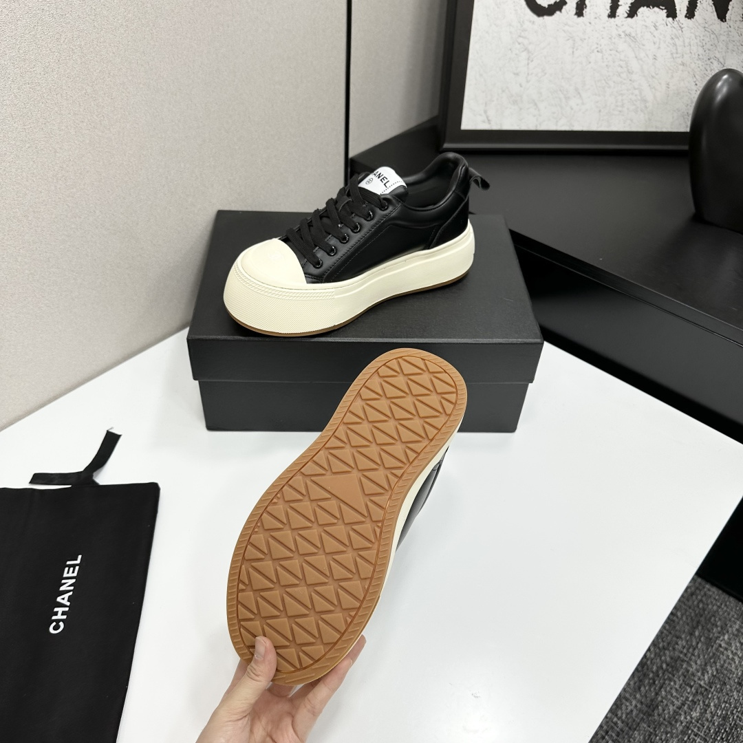 A pair of Chanel black leather sneakers with a thick cream platform sole placed on a black designer box. - Hình 4