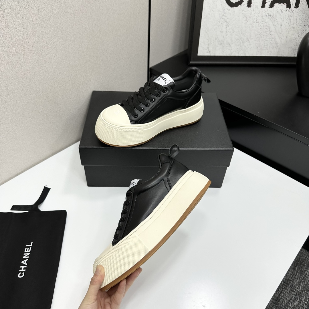 A pair of Chanel black leather sneakers with a thick cream platform sole placed on a black designer box. - Hình 3