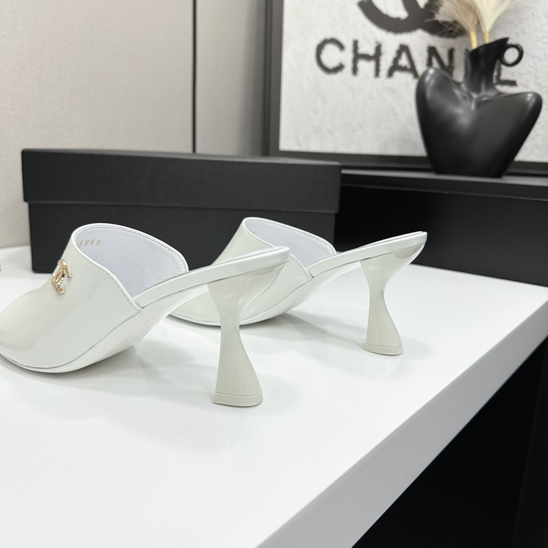 A pair of Chanel white patent leather open-toe mules with gold CC logo and flared heels on a black box. - Hình 7