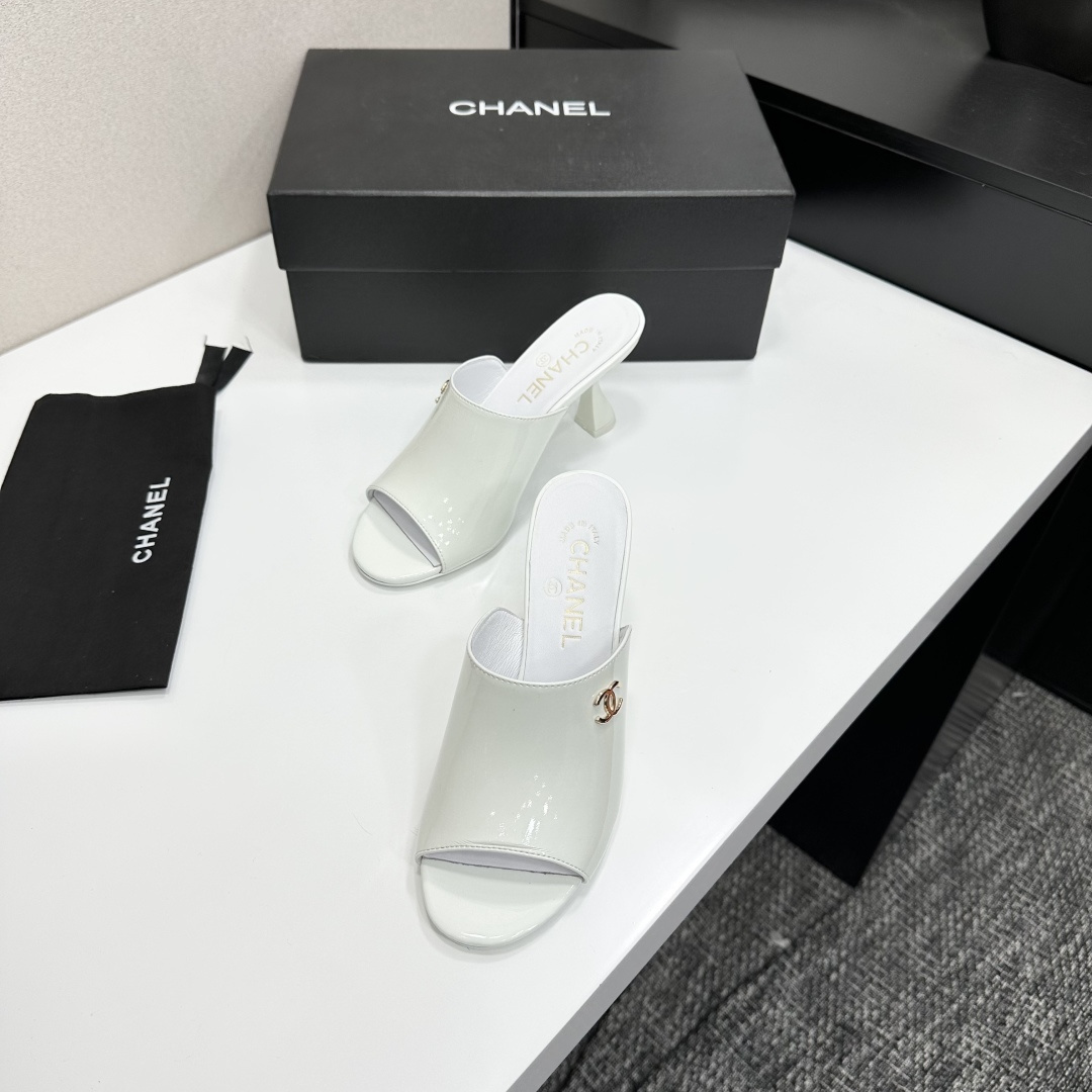 A pair of Chanel white patent leather open-toe mules with gold CC logo and flared heels on a black box. - Hình 5