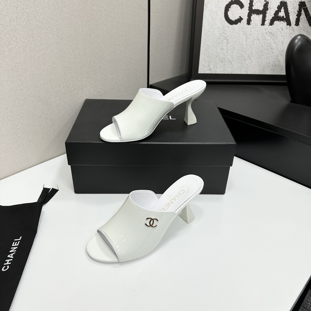 A pair of Chanel white patent leather open-toe mules with gold CC logo and flared heels on a black box. - Hình 2