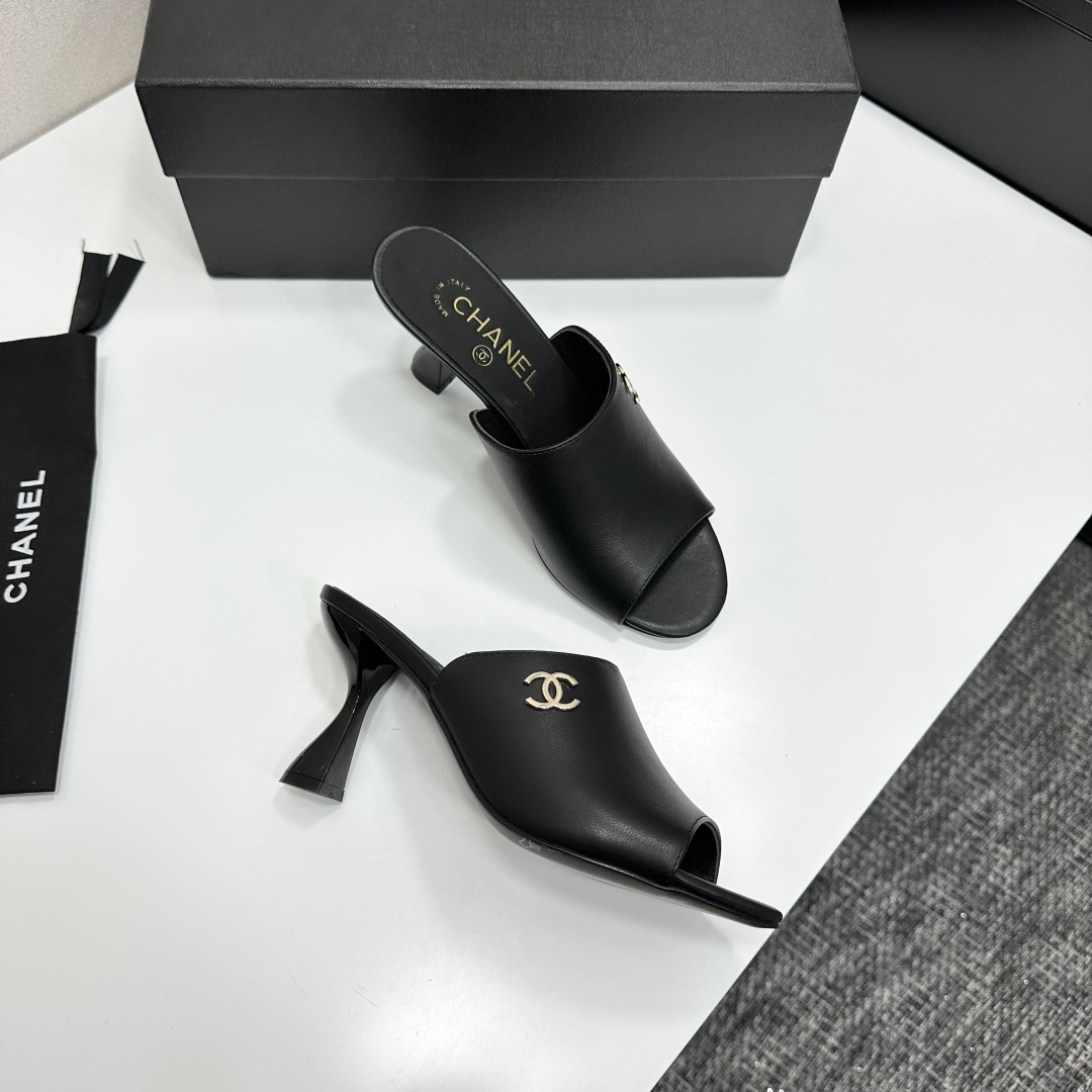 A pair of luxury Chanel black leather mule sandals with gold CC logos resting on a branded black box. - Hình 10