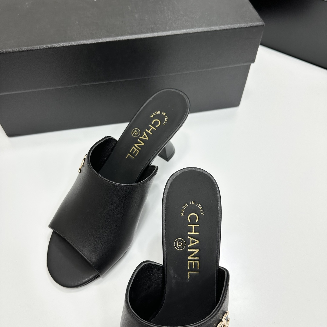 A pair of luxury Chanel black leather mule sandals with gold CC logos resting on a branded black box. - Hình 8