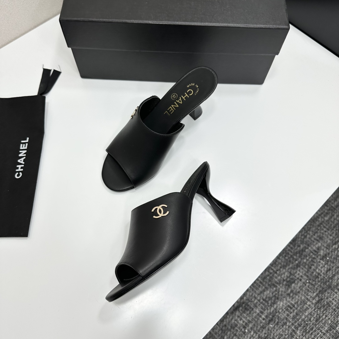 A pair of luxury Chanel black leather mule sandals with gold CC logos resting on a branded black box. - Hình 7