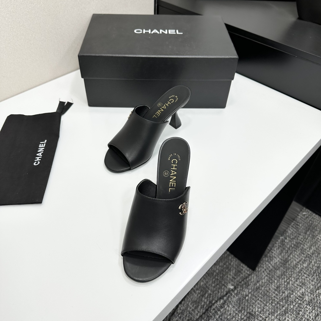 A pair of luxury Chanel black leather mule sandals with gold CC logos resting on a branded black box. - Hình 6