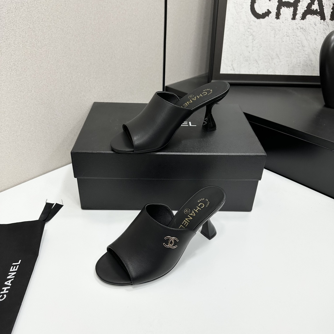 A pair of luxury Chanel black leather mule sandals with gold CC logos resting on a branded black box. - Hình 3