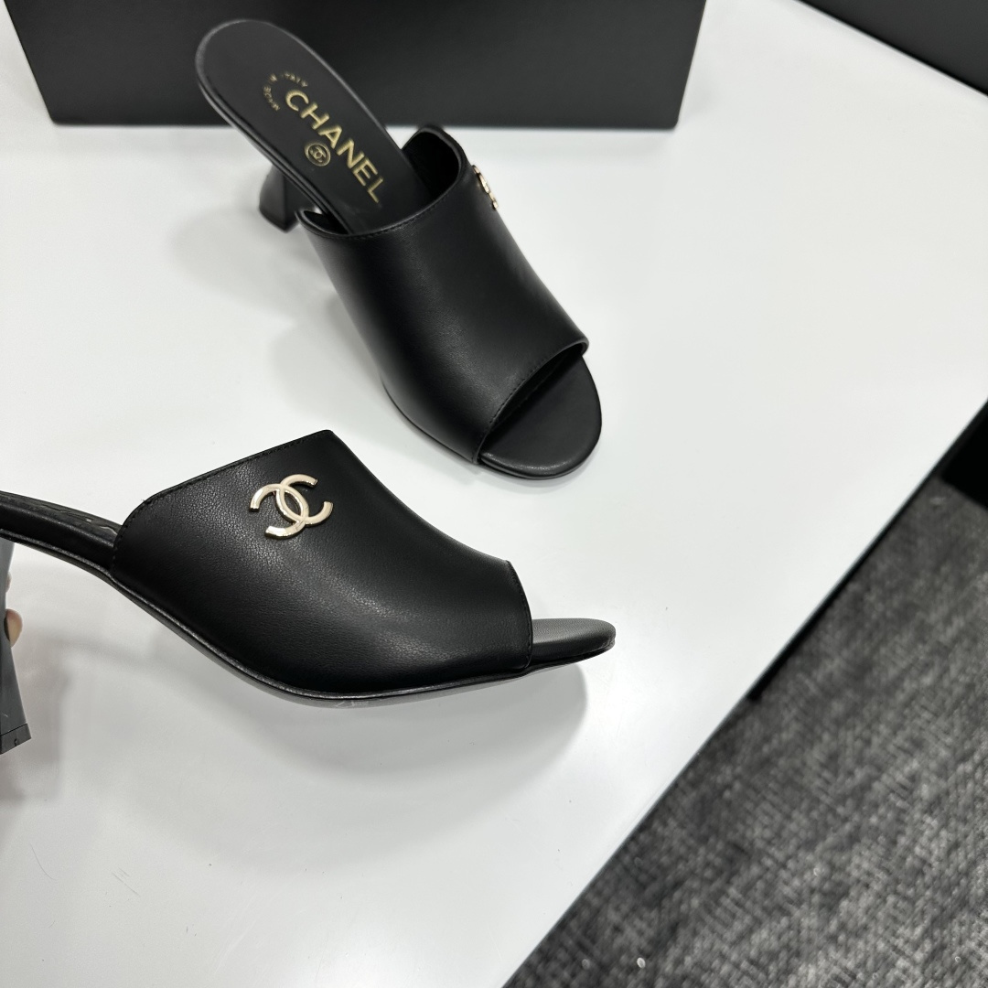 A pair of luxury Chanel black leather mule sandals with gold CC logos resting on a branded black box. - Hình 2