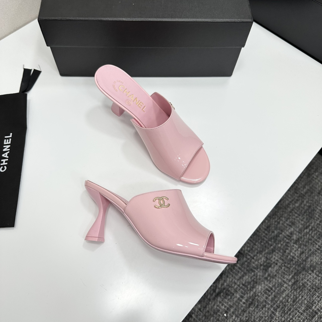 A pair of pink Chanel patent leather mules with gold CC logo and sculpted heels displayed on a black designer box. - Hình 8