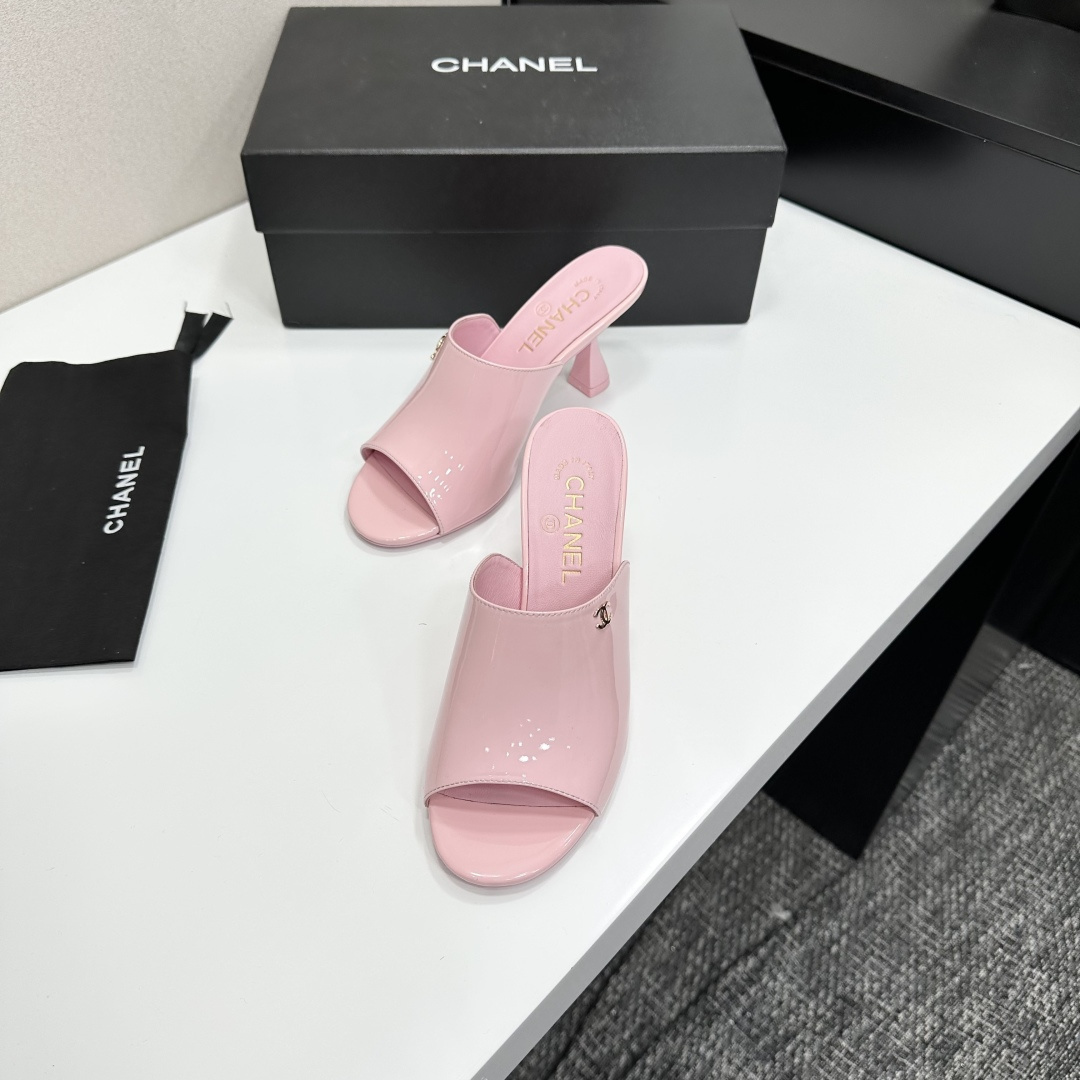 A pair of pink Chanel patent leather mules with gold CC logo and sculpted heels displayed on a black designer box. - Hình 5