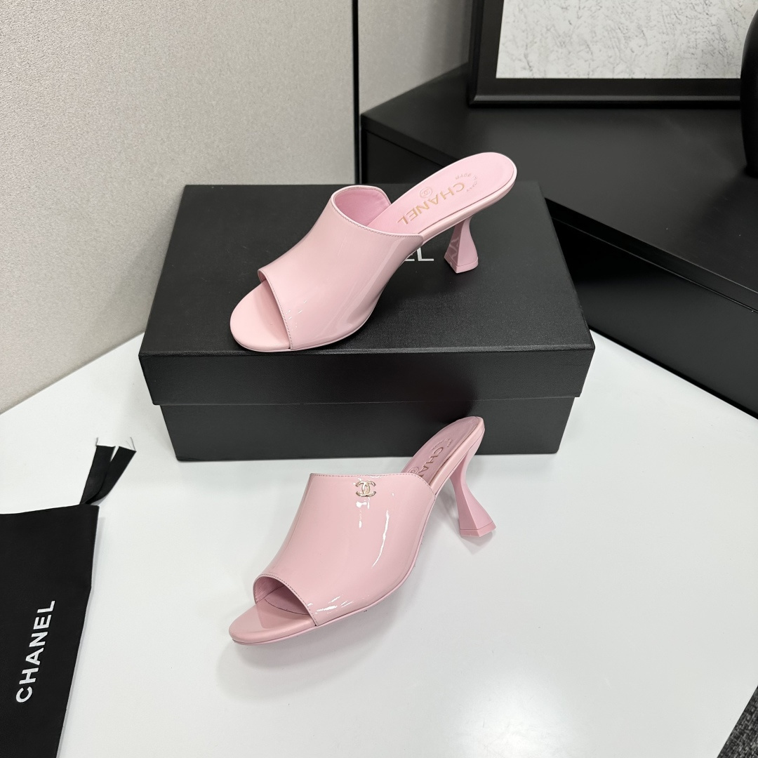 A pair of pink Chanel patent leather mules with gold CC logo and sculpted heels displayed on a black designer box. - Hình 3