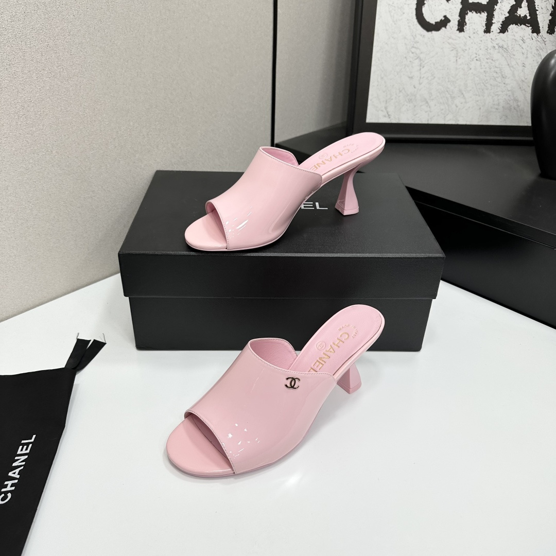 A pair of pink Chanel patent leather mules with gold CC logo and sculpted heels displayed on a black designer box. - Hình 2