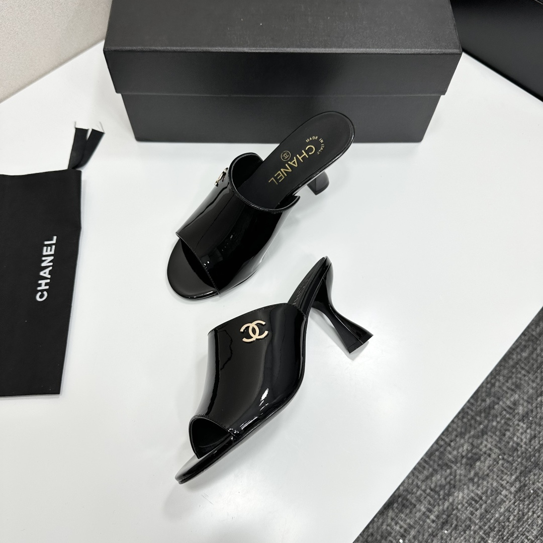 Pair of Chanel black patent leather mules with gold CC logo and sculptural high heels displayed on a black designer box. - Hình 7