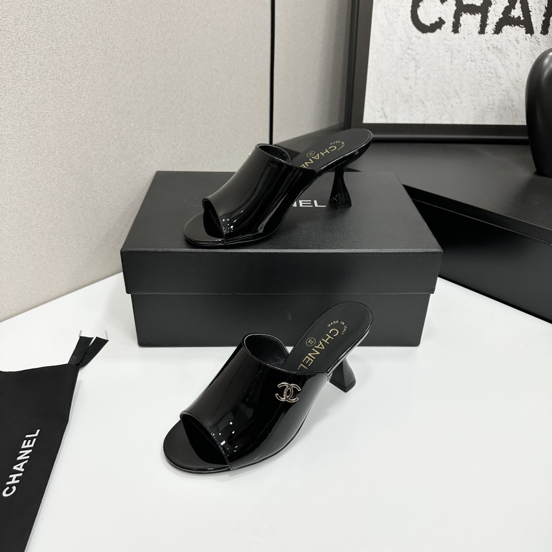 Pair of Chanel black patent leather mules with gold CC logo and sculptural high heels displayed on a black designer box. - Hình 3