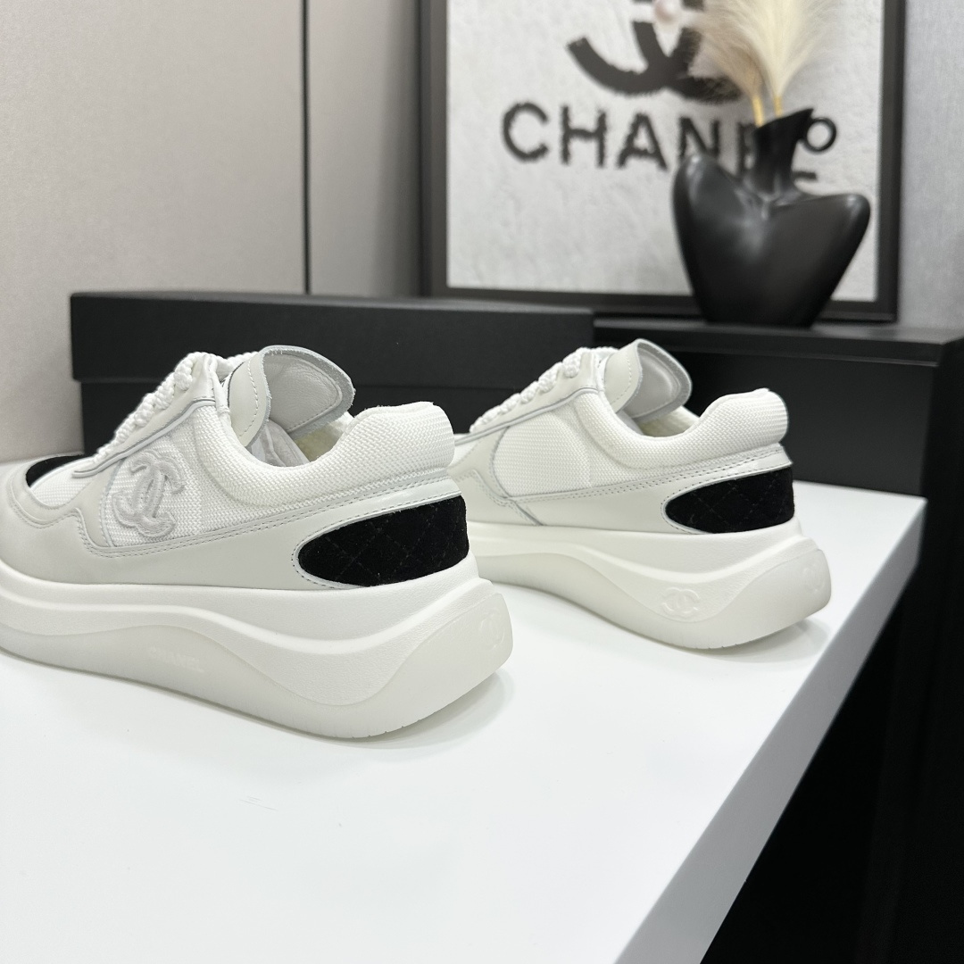 A pair of Chanel white mesh sneakers with black accents and a chunky white sole sitting on a black designer box. - Hình 8