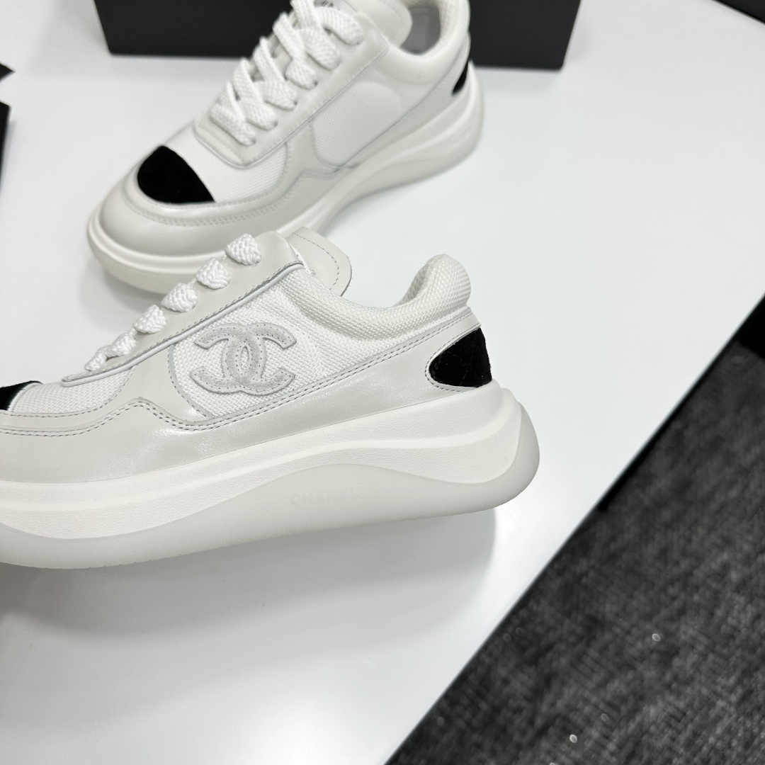 A pair of Chanel white mesh sneakers with black accents and a chunky white sole sitting on a black designer box. - Hình 7