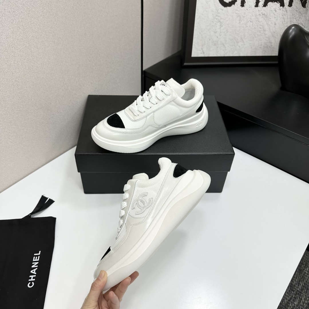 A pair of Chanel white mesh sneakers with black accents and a chunky white sole sitting on a black designer box. - Hình 4