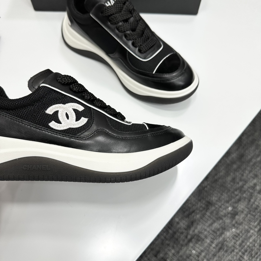 A pair of Chanel black and white mesh leather sneakers with the white interlocking CC logo on the side, placed on a black Chanel shoe box. - Hình 10