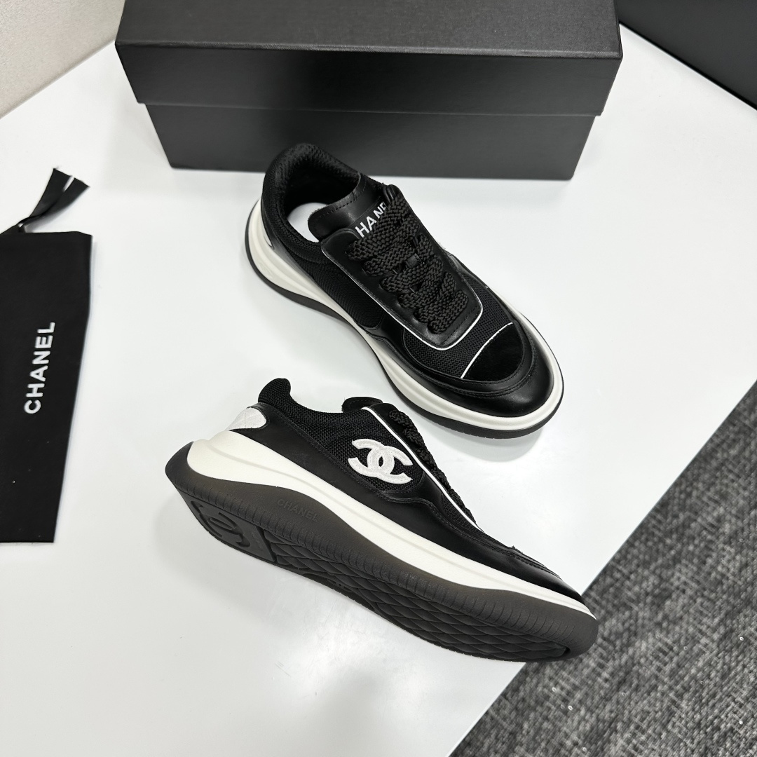 A pair of Chanel black and white mesh leather sneakers with the white interlocking CC logo on the side, placed on a black Chanel shoe box. - Hình 9