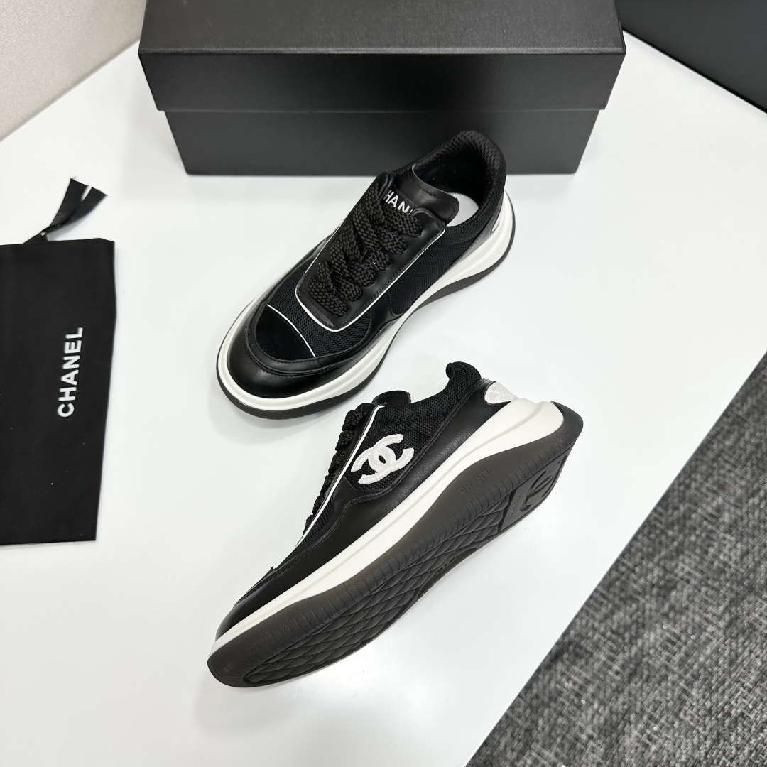A pair of Chanel black and white mesh leather sneakers with the white interlocking CC logo on the side, placed on a black Chanel shoe box. - Hình 6