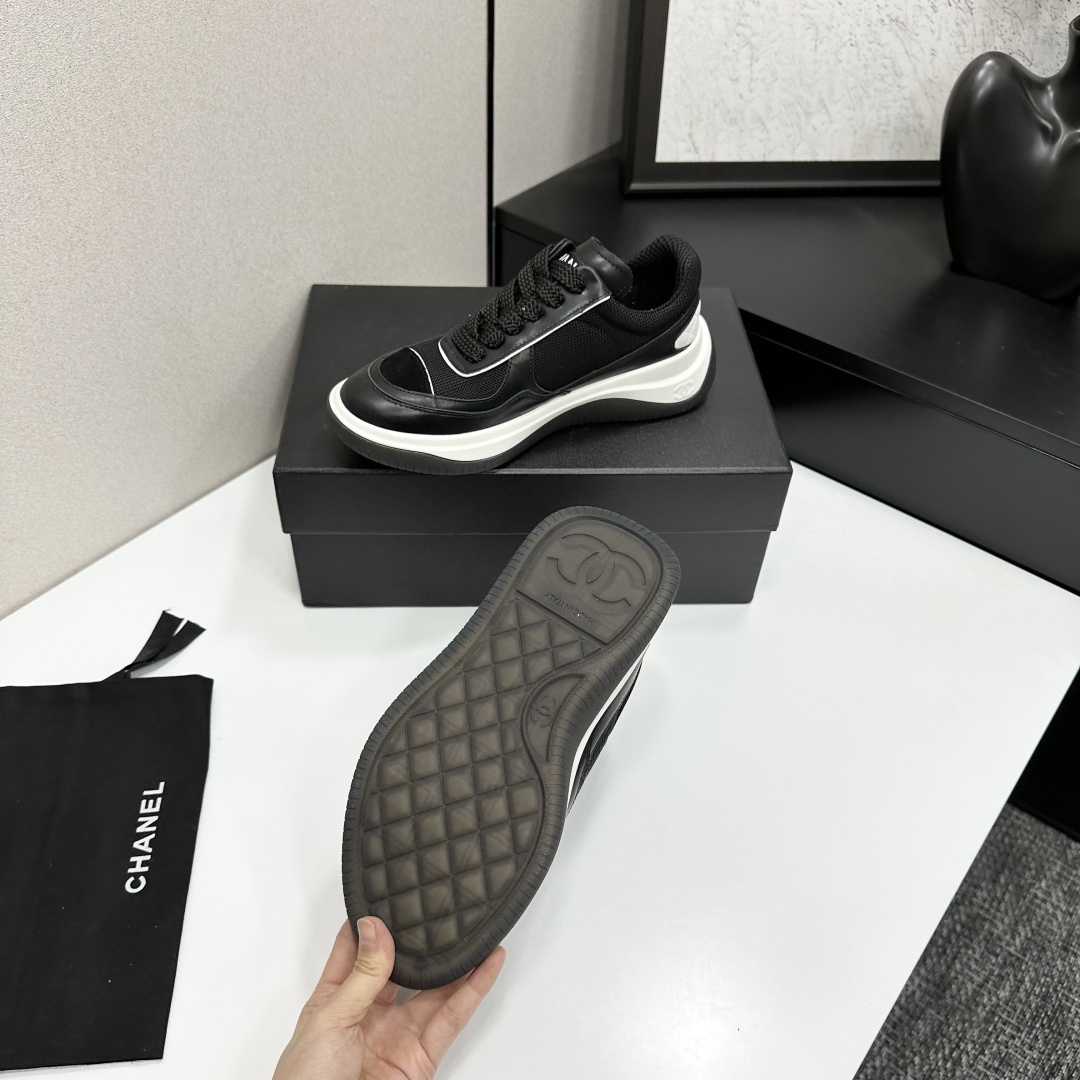 A pair of Chanel black and white mesh leather sneakers with the white interlocking CC logo on the side, placed on a black Chanel shoe box. - Hình 5