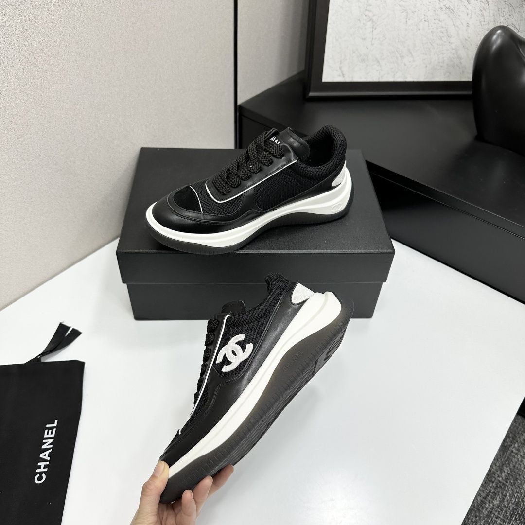 A pair of Chanel black and white mesh leather sneakers with the white interlocking CC logo on the side, placed on a black Chanel shoe box. - Hình 4