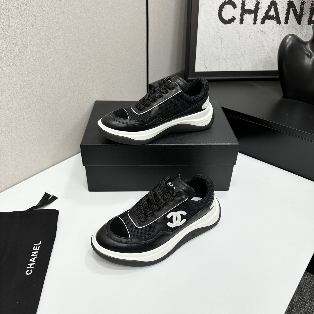 A pair of Chanel black and white mesh leather sneakers with the white interlocking CC logo on the side, placed on a black Chanel shoe box. - Hình 3