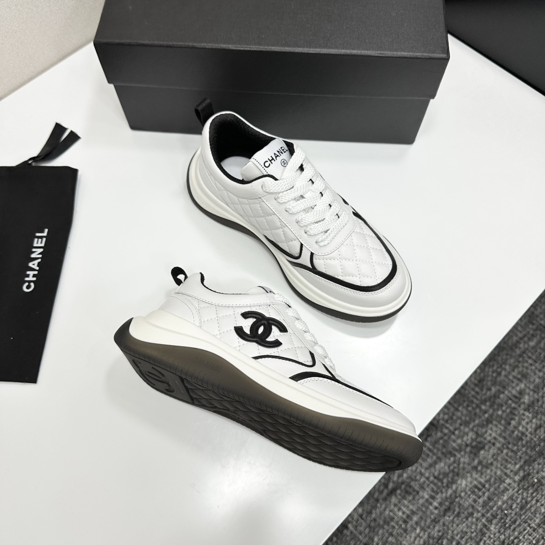 A pair of luxury Chanel white quilted leather sneakers with black CC logo and chunky soles displayed on a black box. - Hình 9