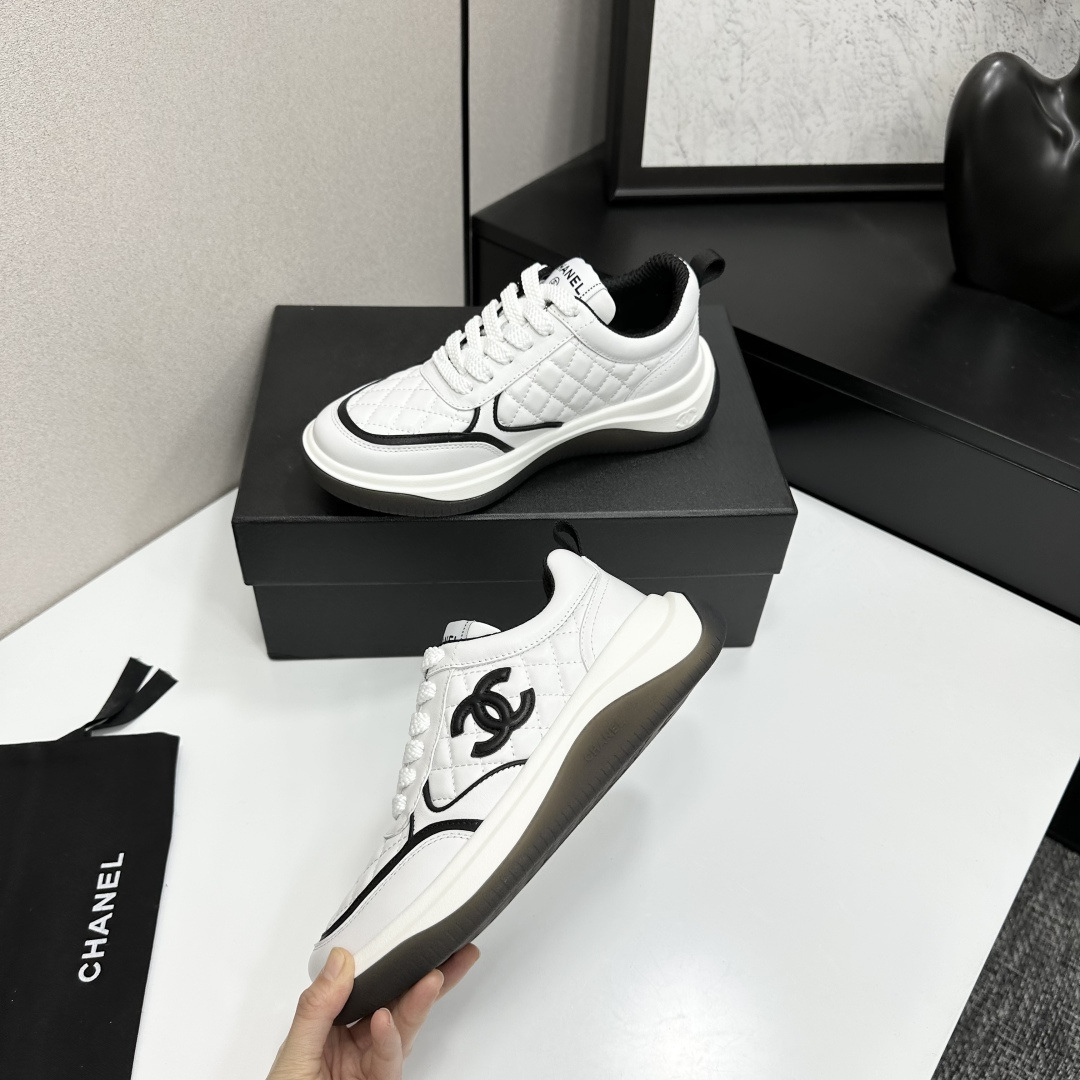 A pair of luxury Chanel white quilted leather sneakers with black CC logo and chunky soles displayed on a black box. - Hình 4