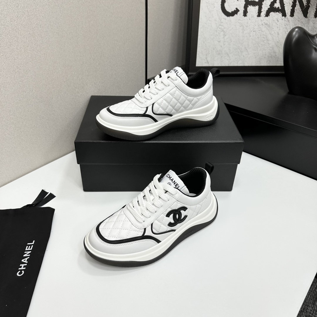 A pair of luxury Chanel white quilted leather sneakers with black CC logo and chunky soles displayed on a black box. - Hình 3