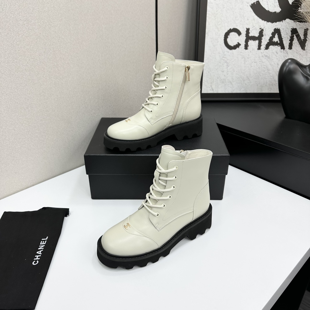 A pair of Chanel ivory leather lace-up combat boots with black chunky lug soles and gold CC logo on the toe cap. - Hình 2