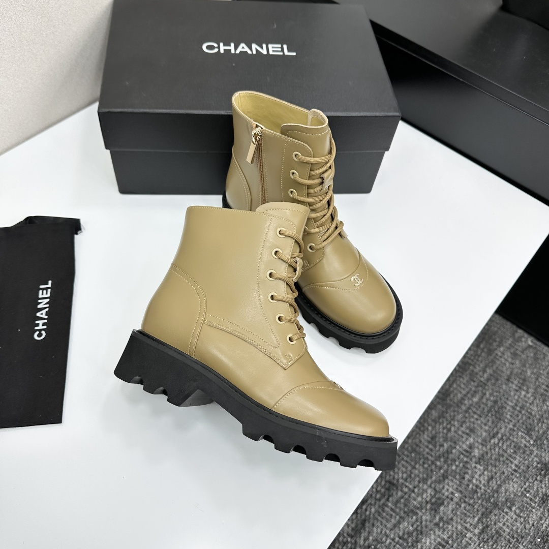 Pair of beige designer leather combat boots with chunky black soles and side zippers displayed on a black box. - Hình 9