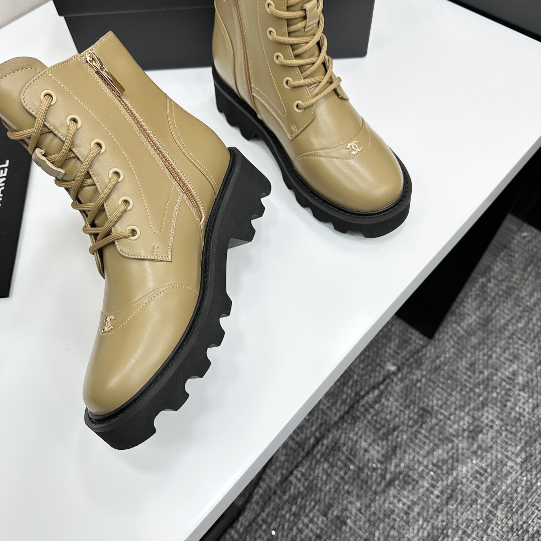 Pair of beige designer leather combat boots with chunky black soles and side zippers displayed on a black box. - Hình 8